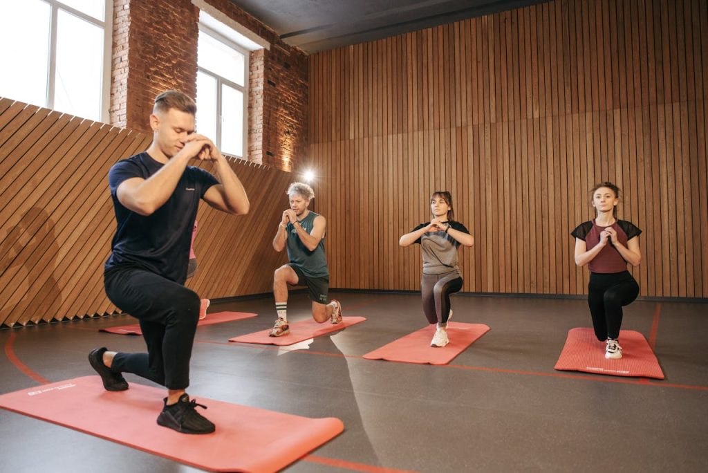 Adults practicing exercises on yoga mats in a contemporary studio setting.